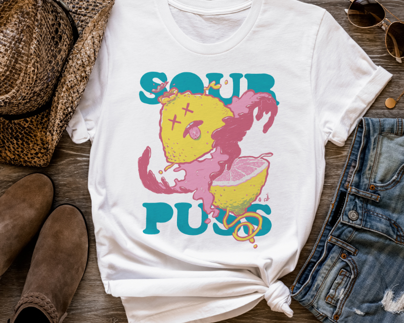 Mockup of a tee shirt with a very juicy lemon sliced in half over the words Sour Puss.